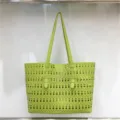 Detail shot of green laser cut geometric pattern tote bag surface and double handles. - Green