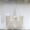 Close-up of the elegant white leather tote bag featuring intricate laser-cut perforated patterns. - White