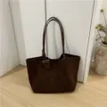 Close-up detail of the brown faux suede tote bag showcasing its minimalist strap design and texture. - Coffee