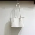 Detailed view of the white woven leather shoulder bag showcasing texture and fine craftsmanship. - White