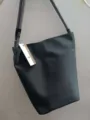 Vista dettagliata di un'elegante borsa a secchiello in nylon grigio con manici e etichetta. - Cinghia Grigia / Grigio