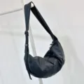 Close-up view of the minimalist black nylon crescent shoulder bag hanging on rack. - Black - Waterproof