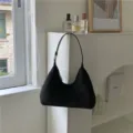 Detailed view of a soft black plush underarm hobo bag, cozy winter accessory texture. - Black