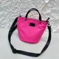 Details of pink waterproof nylon bucket bag with black handles and adjustable crossbody strap. - Rose Red