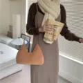 Close-up detail of a soft brown plush hobo shoulder bag worn in a cozy indoor lifestyle setting. - Camel