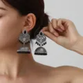 Vintage silver ethnic jhumka earrings detail shot with intricate carved patterns and black bead tassels. - Black