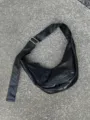 Detailed view of the black slouchy leather hobo dumpling shoulder bag strap metal buckle. - Black