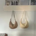 Detail view of soft leather hobo shoulder bags hanging on wall, showing smooth texture and dumpling shape. - Brown