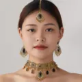 Close-up detail of ethnic gold-toned choker necklace and matching earrings set with black stones. - Black