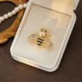 Close-up detail of exquisite bee brooch featuring shiny rhinestones, pearl head and gold tone. - Style 1