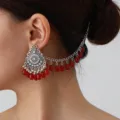 Close-up detail of bohemian vintage silver drop earring and hair chain with red beads. - Red