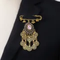 Detailed view of bohemian vintage gold brooch with pink crystal and coin tassel charms. - Pink