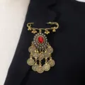Vintage gold-tone brooch with red rhinestone center and hanging coin charms for chic style. - Red