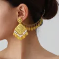 Detailed close-up of ethnic filigree geometric earring with amber beads and pearls. - Golden