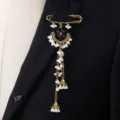 Elegant ethnic gold safety pin brooch featuring black crystals, white pearls and long tassels. - Black