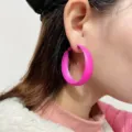 Close-up detail of bold pink hoop earrings worn on ear, stylish minimalist geometric design. - Rose Red
