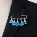 Detailed close-up of a vintage boho silver bell tassel brooch with blue beaded charms. - Blue