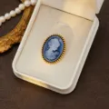 Close-up detail view of vintage blue cameo brooch in white jewelry box with pearls. - Style 12 (Blue Relief)