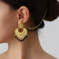 Detailed shot of Indian ethnic vintage gold-colored carved ear chain with black bead tassels. - Gold Black