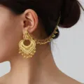 Detailed shot of ethnic carved ear chain and retro tassel earrings, vintage gold tone style. - Gold