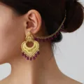 Close-up detail shot of vintage ethnic gold-toned hollow carved earrings with purple bead ear chain. - Gold Purple