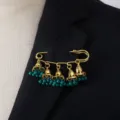 Close-up details of retro court style bell tassel brooch with green beads pinned on suit lapel. - Green