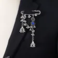 Close-up detail of silver bohemian tassel brooch with blue crystal and bells on black suit. - Blue