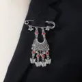 Detail shot of a bohemian vintage carved rhinestone tassel brooch pin on lapel, elegant jewelry. - Red