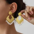 Retro gold-toned geometric drop earrings featuring ornate engraved patterns and delicate pearl fringe detail. - Gold White
