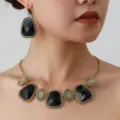 Close-up detail of vintage gold-tone ethnic choker necklace and matching geometric earrings set. - Gold Black