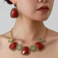 Detail shot of ethnic retro red stone necklace earrings set in gold textured frame. - Gold Red