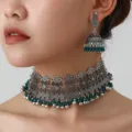 Close-up detail of bohemian silver choker necklace and jhumka earrings set with green beads. - Silver Green