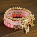 Detailed view of multi-layer pink crystal beaded bracelet set with gold butterfly charms. - Pink