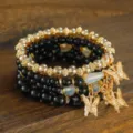 Detailed close-up view of the layered beaded bracelet with elegant gold butterfly charms. - Black