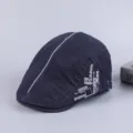 Closeup detail of dark blue cotton ivy cap featuring central grey stripe and side embroidery text. - Adjustable / Navy Blue