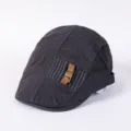 Detailed close-up of dark grey stylish flat cap with decorative leather strap and metal buckle. - Adjustable / C - Dark Gray