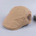 Close-up detail of a classic khaki cotton flat cap with side embroidered fashion patch. - Adjustable / Beige