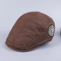 Close-up of brown cotton flat cap, vintage newsboy hat detail with side embroidered badge. - Adjustable / Brown