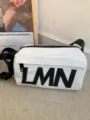 Detail view of white waterproof pillow crossbody bag with black LMN letters and strap for sports. - White