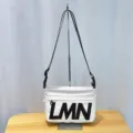 Detail shot of white crossbody shoulder bag with black LMN letters and strap on stand. - New Style White