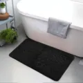 Detail view of the black embossed flannel bath mat placed in a clean modern bathroom. - Diamond Pattern Black