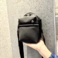 Detailed view of a compact black crossbody bag featuring durable fabric and handy zipper pocket. - Black