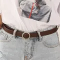 Vrouwen smalle bruine lederen riem met ronde metalen gesp, stijlvol retro jeansaccessoire voor dag. - Ronde Gesp / koffiekleur