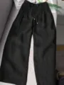 Detail view of black casual wide leg trousers featuring high waist design and comfort drawstring. - XS / Black