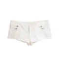 Detailed view of white denim hot pants featuring metallic decorative buttons and pleated side design. - XS / Bottoms / White