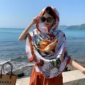 Outdoor seaside detail view of a stylish floral print sun protection scarf and shawl. - 2316