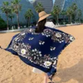 Outdoor detail view showing a dark blue floral pattern beach shawl and scarf product. - 311
