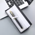 Detailed close-up view of a luxury metal ballpoint pen elegantly presented in a black gift box. - Black Pen With Gold Clip / 041 Pen Box
