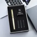 Close-up van gouden gegraveerde vulpen cadeaupakket met inktfles en patronen op bureau. - 30#