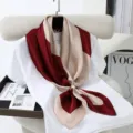 Close-up detail of color-blocked silk scarf with pearl buckle accessory on display. - Style 3
